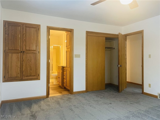 unfurnished bedroom featuring a closet, ensuite bathroom, ceiling fan, and light colored carpet