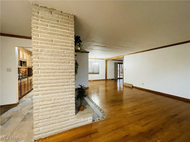 unfurnished living room with light hardwood / wood-style flooring, ornamental molding, and a notable chandelier