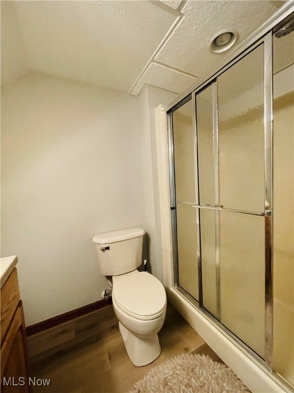 bathroom with toilet, vanity, a shower with shower door, and wood-type flooring