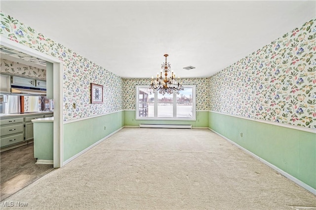 unfurnished dining area featuring wallpapered walls, baseboard heating, a chandelier, carpet flooring, and baseboards
