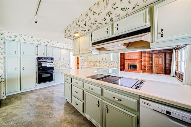 kitchen featuring black appliances, under cabinet range hood, light countertops, decorative backsplash, and wallpapered walls