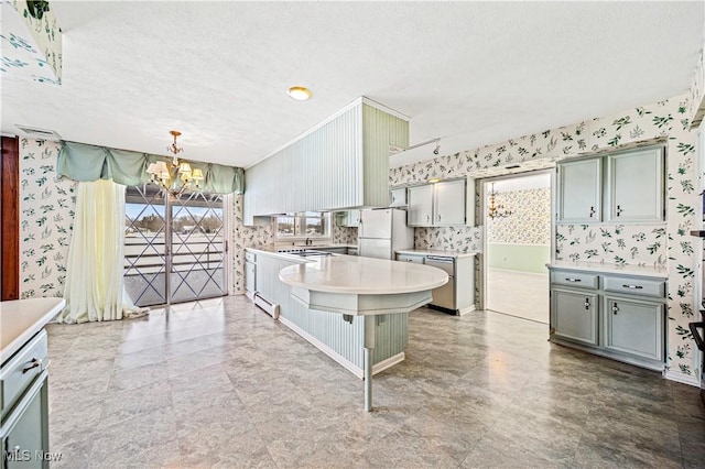 kitchen with wallpapered walls, a chandelier, freestanding refrigerator, a textured ceiling, and light countertops