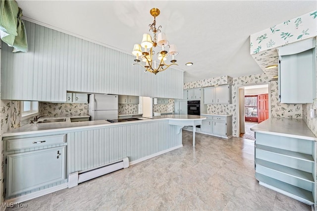 kitchen featuring black electric stovetop, white fridge, sink, hanging light fixtures, and baseboard heating