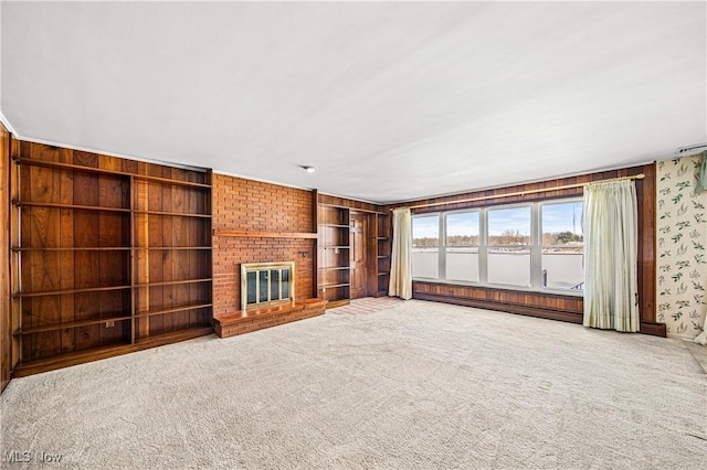 unfurnished living room featuring a baseboard radiator, carpet flooring, a brick fireplace, built in features, and wallpapered walls