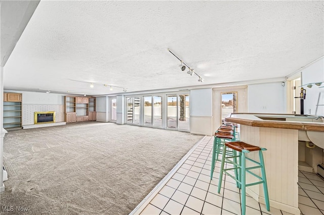 unfurnished living room featuring carpet, a tile fireplace, track lighting, and a textured ceiling