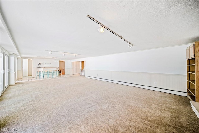 interior space featuring light colored carpet, a textured ceiling, and a baseboard radiator