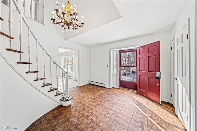 entryway with a baseboard heating unit, stairs, a chandelier, and baseboards