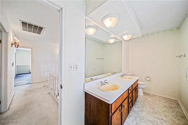 bathroom with toilet, double vanity, and baseboards