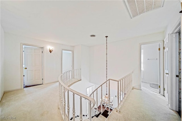 hallway featuring carpet flooring, an upstairs landing, and baseboards