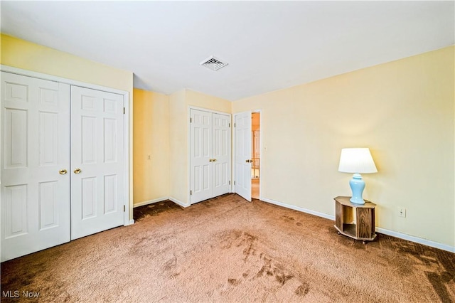unfurnished bedroom featuring carpet flooring, baseboards, and two closets