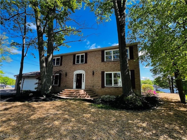 colonial house featuring brick siding and an attached garage