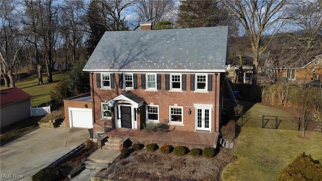 colonial inspired home with a garage and a front lawn