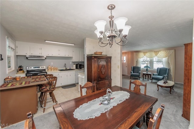 dining space featuring a textured ceiling, a notable chandelier, light colored carpet, and sink