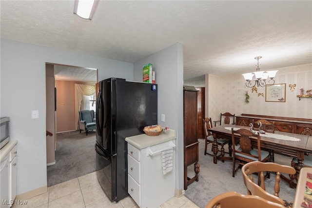 kitchen with an inviting chandelier, a textured ceiling, decorative light fixtures, light carpet, and black refrigerator