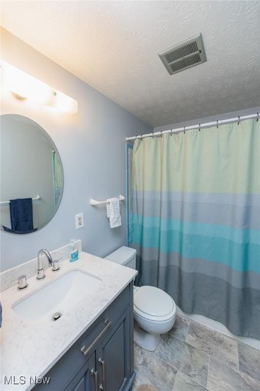 bathroom with a shower with shower curtain, vanity, toilet, and a textured ceiling