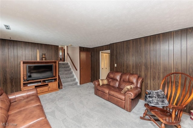 living room featuring light colored carpet, a textured ceiling, and wooden walls