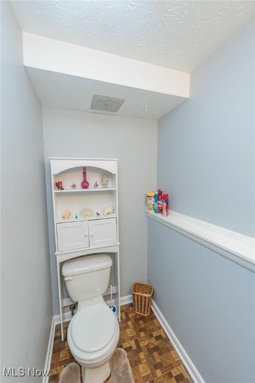 bathroom featuring parquet floors, a textured ceiling, and toilet