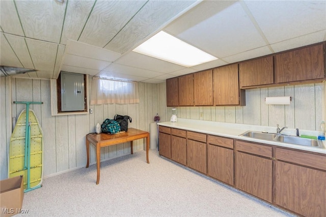 kitchen with a drop ceiling, light colored carpet, sink, and electric panel