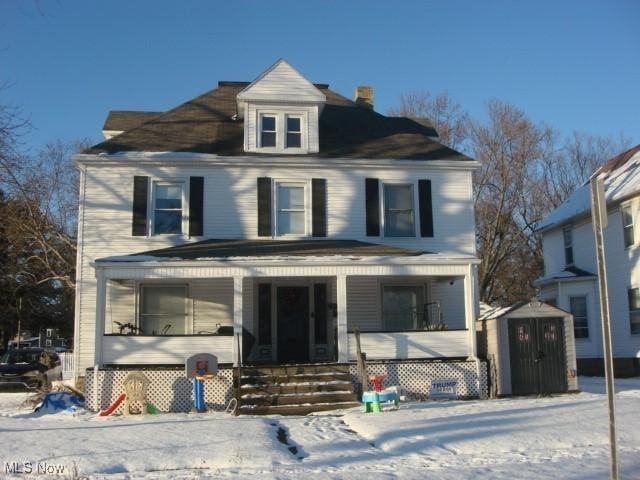 front of property featuring a porch and a storage shed