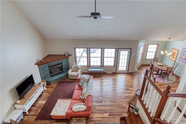 living room with a tile fireplace, a healthy amount of sunlight, ceiling fan with notable chandelier, and hardwood / wood-style flooring