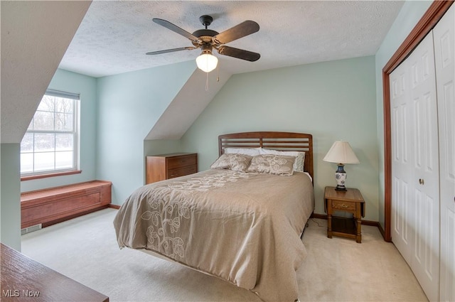 carpeted bedroom featuring ceiling fan, vaulted ceiling, a textured ceiling, and a closet