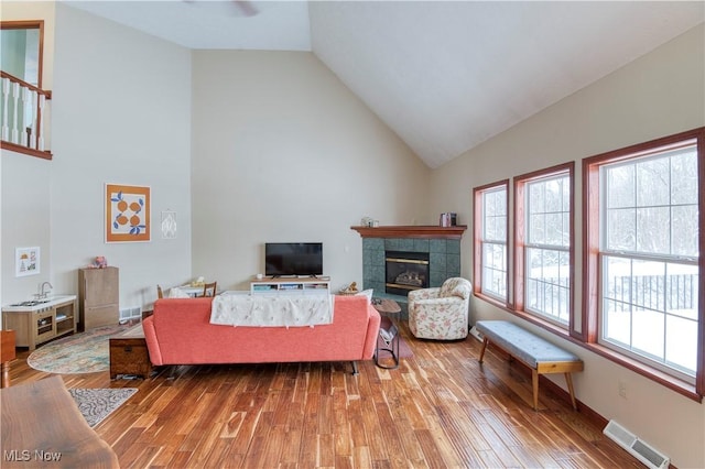 living room featuring light hardwood / wood-style floors, lofted ceiling, and a tiled fireplace