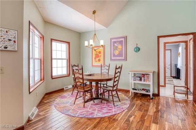 dining room featuring wood-type flooring, an inviting chandelier, and lofted ceiling