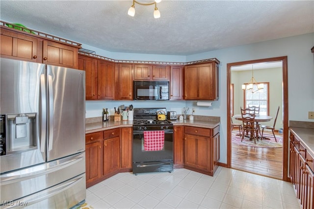 kitchen featuring a textured ceiling, decorative light fixtures, an inviting chandelier, and black appliances