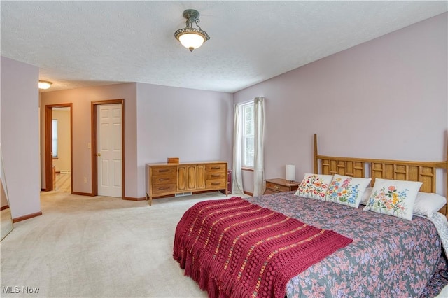 bedroom with light colored carpet and a textured ceiling