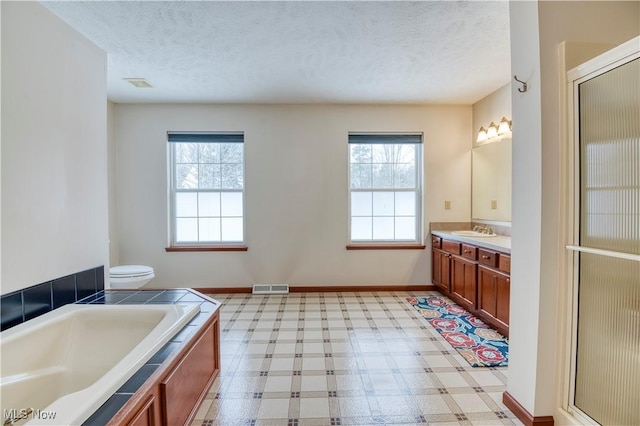 full bathroom with vanity, toilet, a textured ceiling, and a wealth of natural light