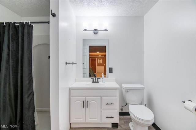 bathroom with a shower with shower curtain, vanity, toilet, and a textured ceiling