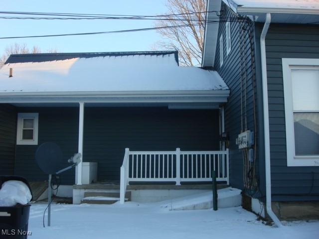 snow covered property entrance featuring a porch