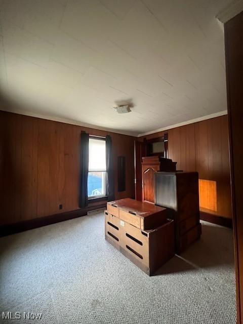 unfurnished bedroom with dark colored carpet and wood walls