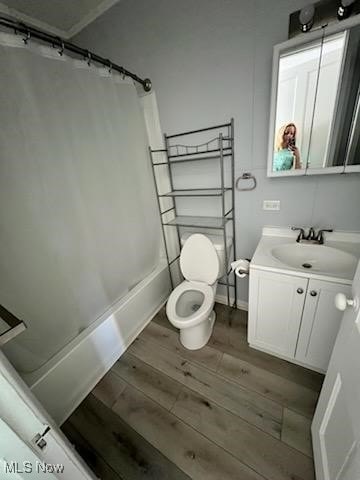 full bathroom featuring hardwood / wood-style flooring, vanity, shower / bath combo with shower curtain, and toilet