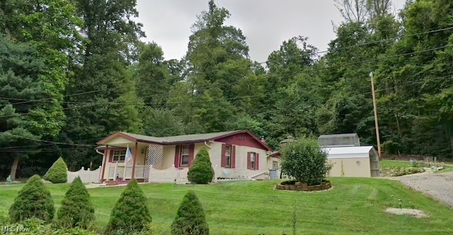 view of front of property with covered porch, a front yard, and a storage shed