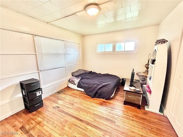 bedroom with light hardwood / wood-style floors and crown molding