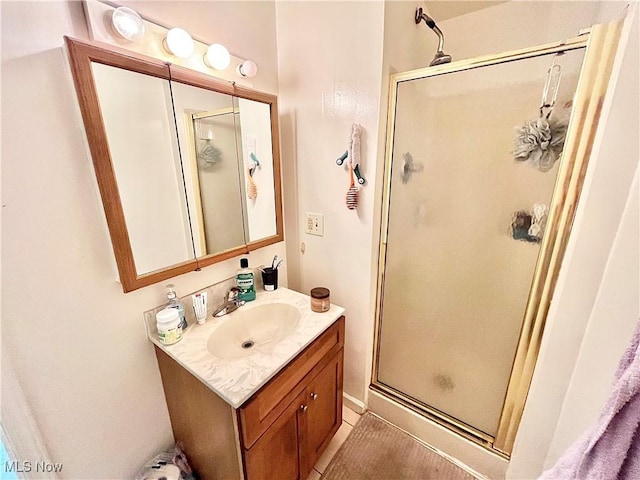 bathroom featuring a shower with door and vanity