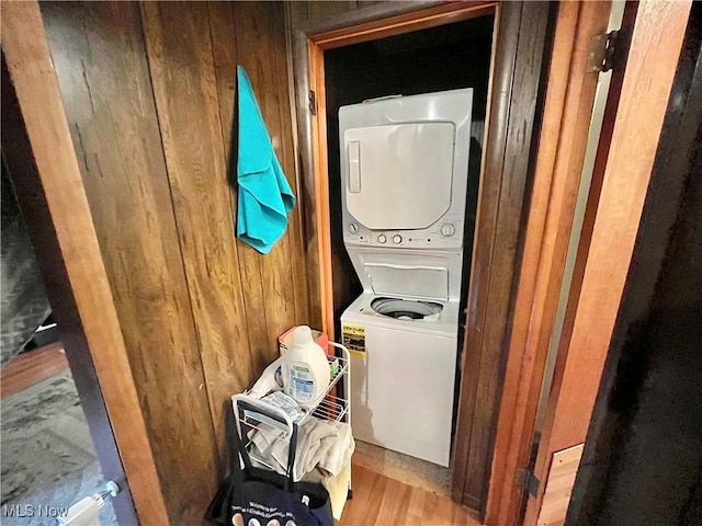 laundry room with stacked washer / dryer and wooden walls