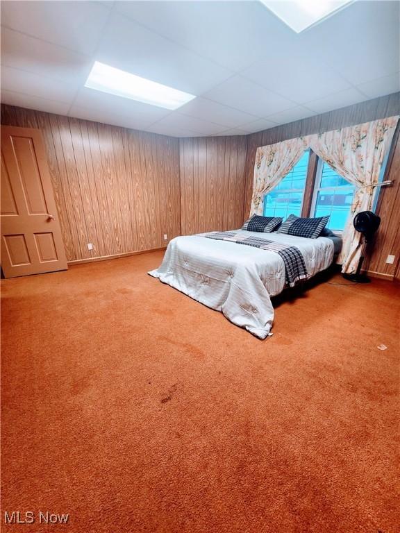 carpeted bedroom with wood walls and a drop ceiling