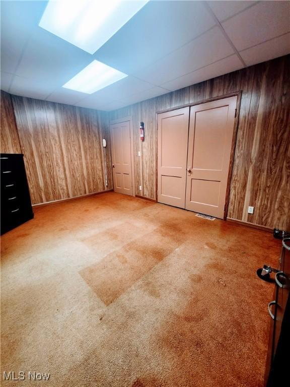 interior space with light colored carpet and wooden walls