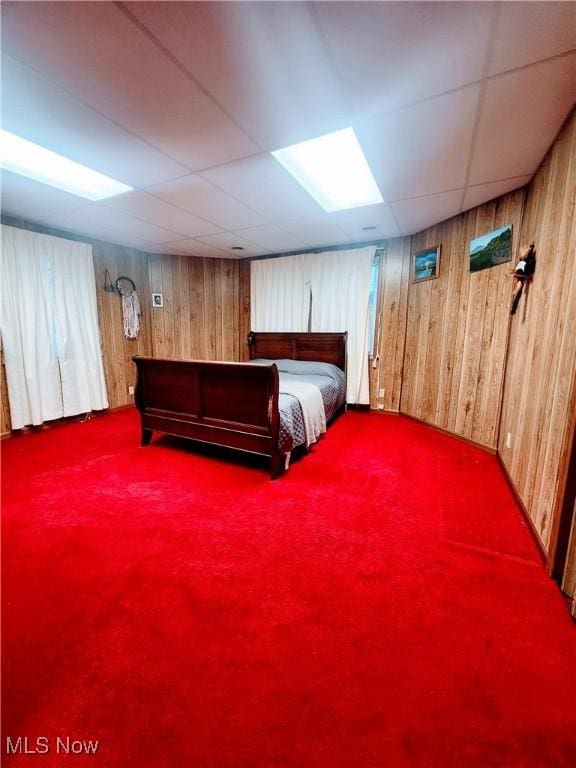 unfurnished bedroom with carpet, a paneled ceiling, and wooden walls