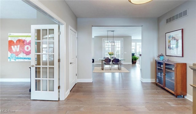 corridor featuring hardwood / wood-style flooring, french doors, and a chandelier