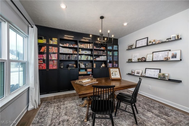 office space with a notable chandelier, dark hardwood / wood-style floors, a healthy amount of sunlight, and a textured ceiling