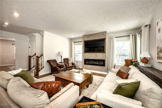 living room with wood-type flooring, a large fireplace, a textured ceiling, and plenty of natural light