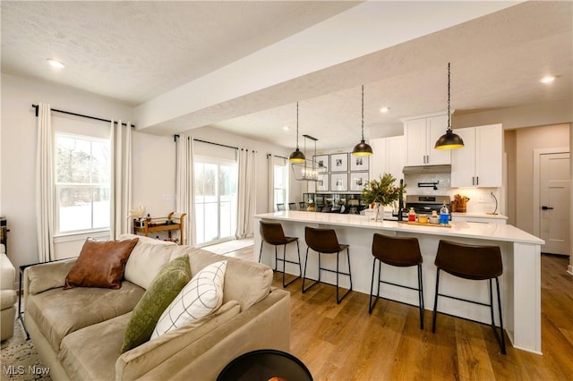 kitchen with stainless steel range, a kitchen breakfast bar, decorative light fixtures, and a kitchen island with sink