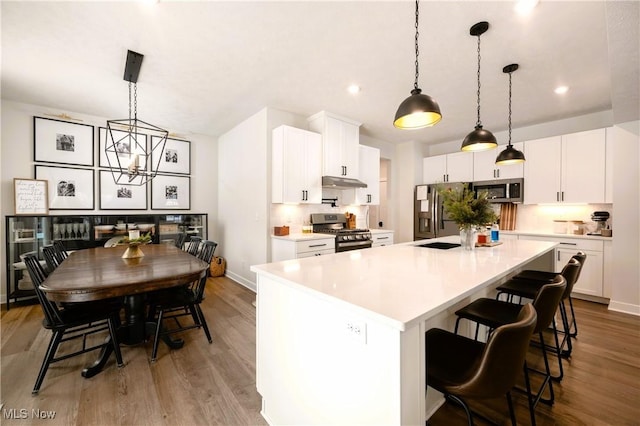 kitchen featuring white cabinets, appliances with stainless steel finishes, and hanging light fixtures