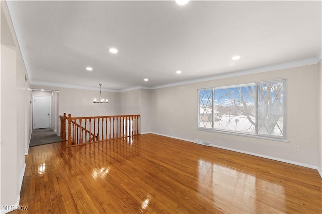 unfurnished room featuring hardwood / wood-style floors, crown molding, and a notable chandelier