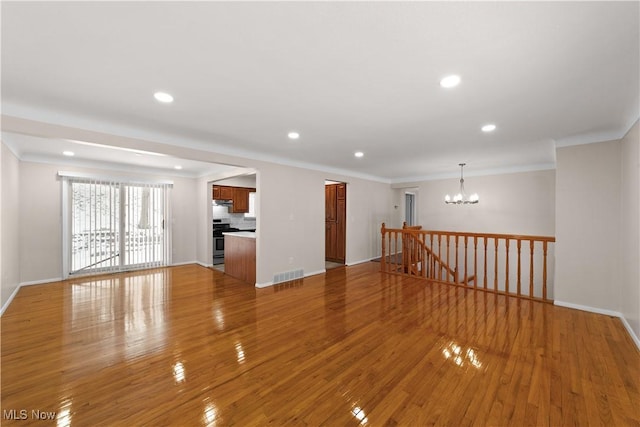 empty room featuring light hardwood / wood-style floors, ornamental molding, and a chandelier