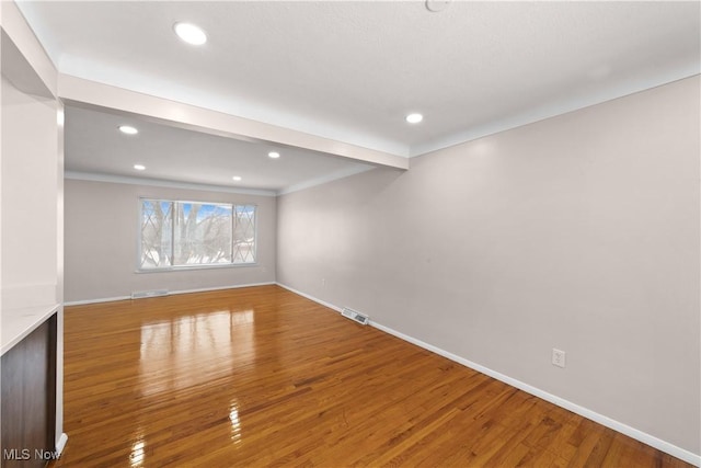 empty room with beam ceiling and wood-type flooring