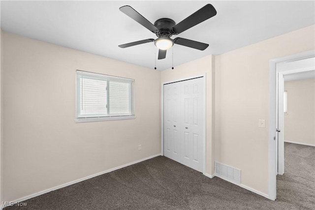 unfurnished bedroom featuring ceiling fan, a closet, and dark colored carpet